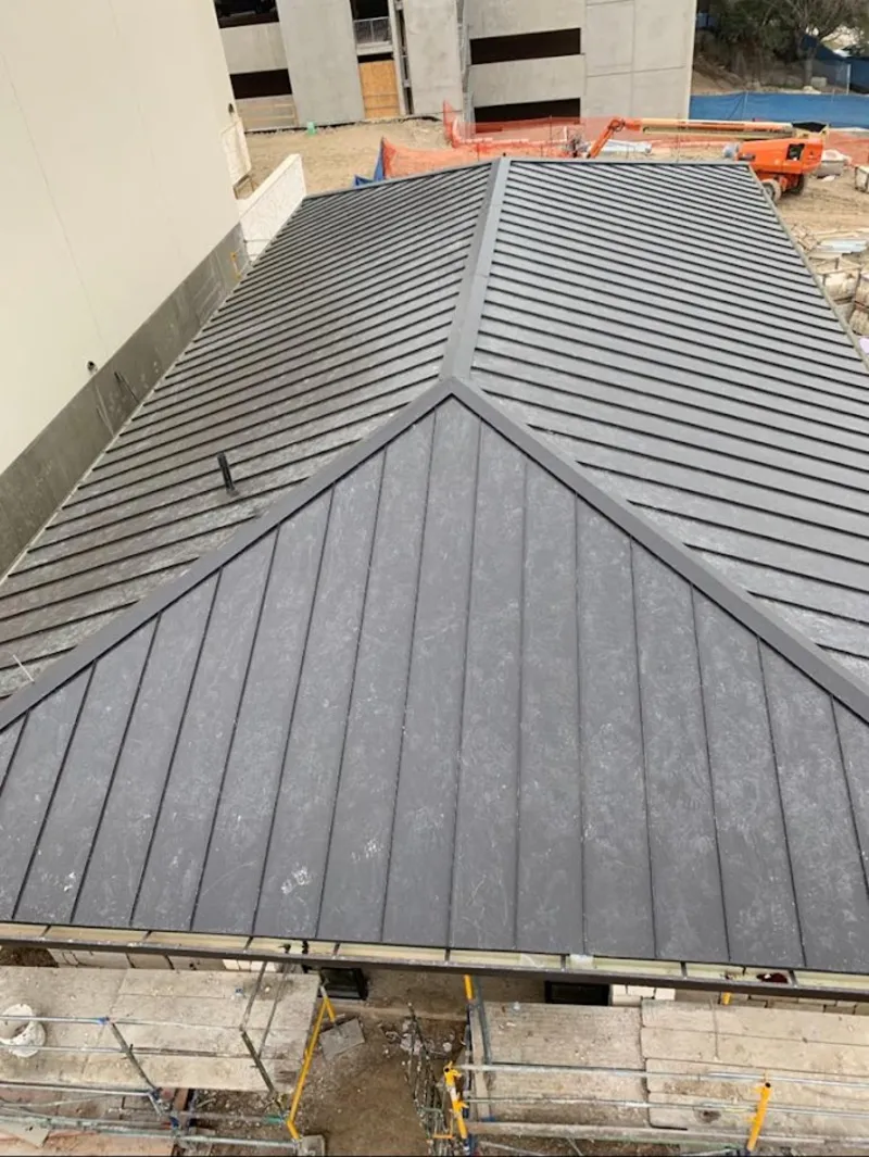 Commercial metal roof construction with crane equipment in Porters Neck